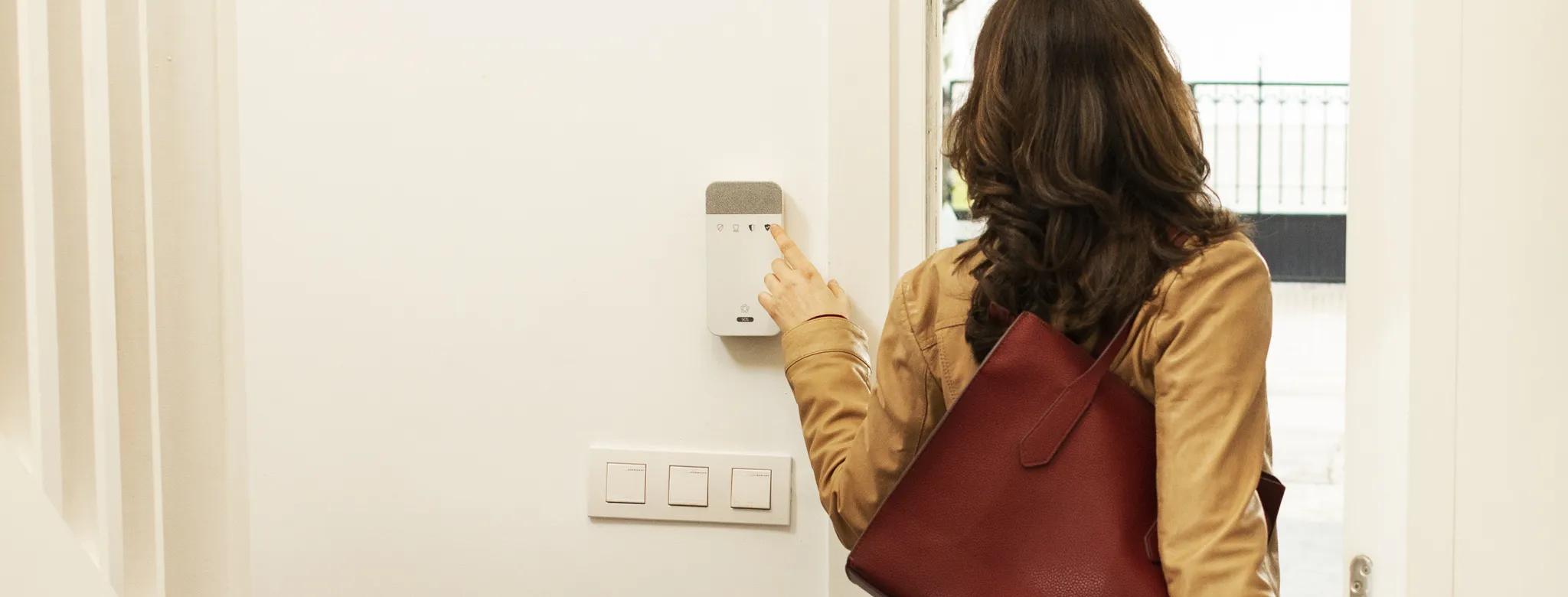 Mujer saliendo de casa activando alarma